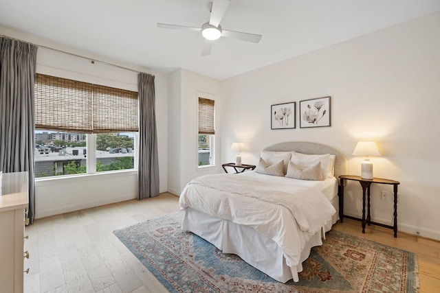 bedroom with ceiling fan, multiple windows, and light hardwood / wood-style flooring