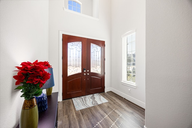 entryway with a towering ceiling, wood-type flooring, and french doors