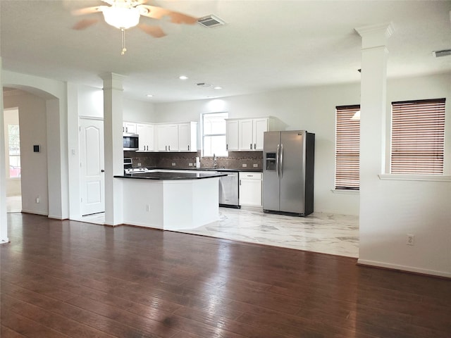 kitchen featuring stainless steel appliances, white cabinetry, decorative columns, and decorative backsplash