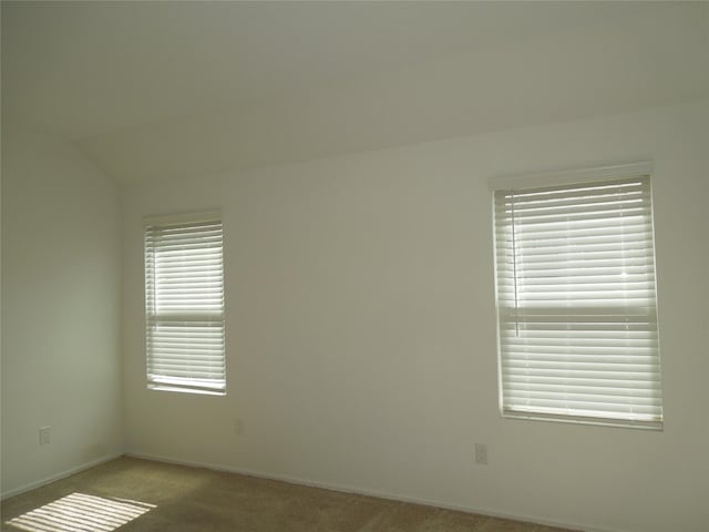 carpeted empty room featuring lofted ceiling