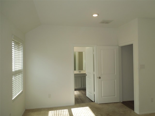 carpeted empty room featuring sink and vaulted ceiling