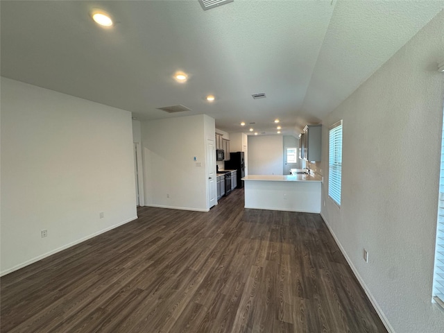 unfurnished living room with dark wood-style flooring, baseboards, visible vents, and recessed lighting
