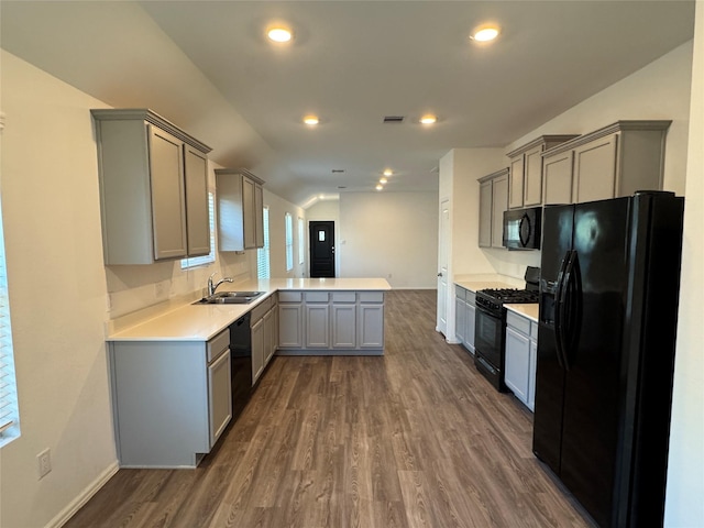 kitchen featuring gray cabinets, a peninsula, black appliances, dark wood finished floors, and a sink