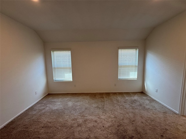 unfurnished room featuring a healthy amount of sunlight, vaulted ceiling, and carpet floors
