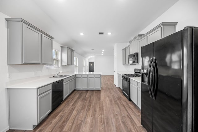18415 Running Shadow Ct, Hockley, TX 77447 - kitchen with black appliances, gray cabinetry, a peninsula, a sink, and wood finished floors