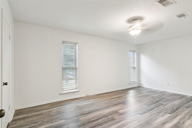 unfurnished room with plenty of natural light, dark hardwood / wood-style floors, and a textured ceiling