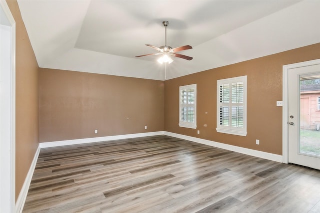 unfurnished room with a raised ceiling, wood-type flooring, vaulted ceiling, and ceiling fan