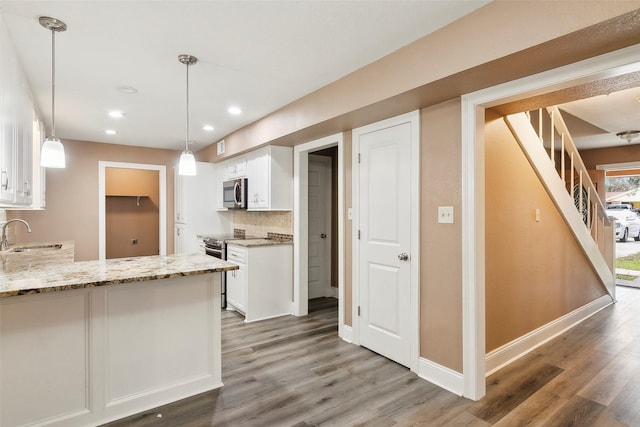 kitchen featuring pendant lighting, stainless steel appliances, dark hardwood / wood-style floors, white cabinets, and decorative backsplash