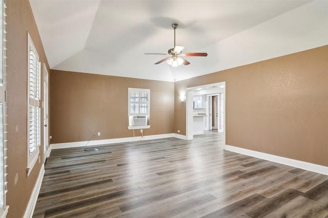 spare room with dark wood-type flooring, a healthy amount of sunlight, and vaulted ceiling