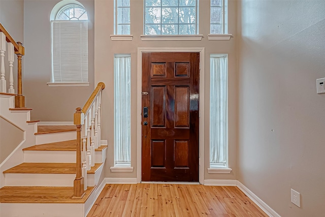 foyer with a towering ceiling and light hardwood / wood-style flooring