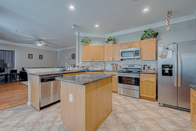 kitchen featuring crown molding, a center island, dark stone countertops, appliances with stainless steel finishes, and kitchen peninsula