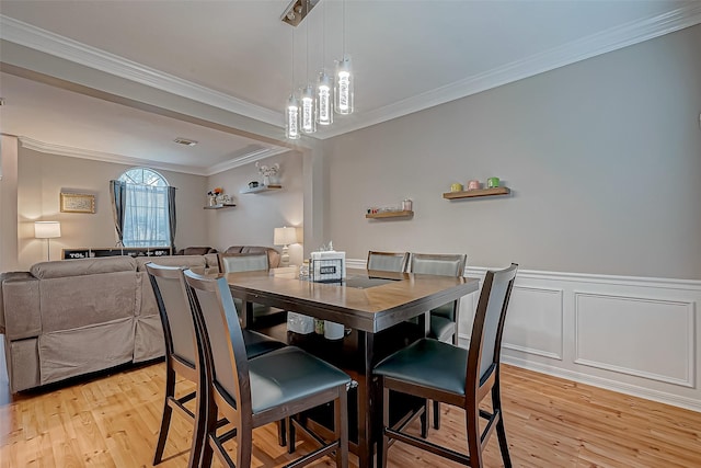 dining room with crown molding and light hardwood / wood-style flooring