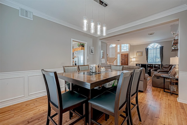 dining area with ornamental molding, a chandelier, and light wood-type flooring