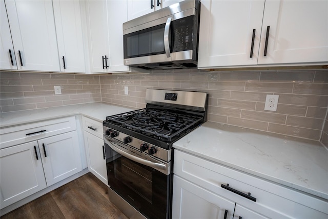 kitchen featuring tasteful backsplash, white cabinetry, appliances with stainless steel finishes, and dark hardwood / wood-style floors