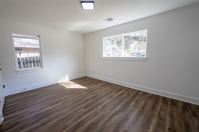 empty room with dark wood-type flooring and a healthy amount of sunlight