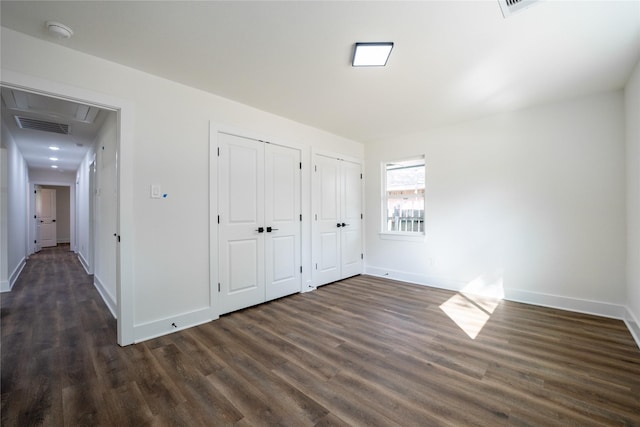 unfurnished bedroom featuring dark wood-type flooring and two closets