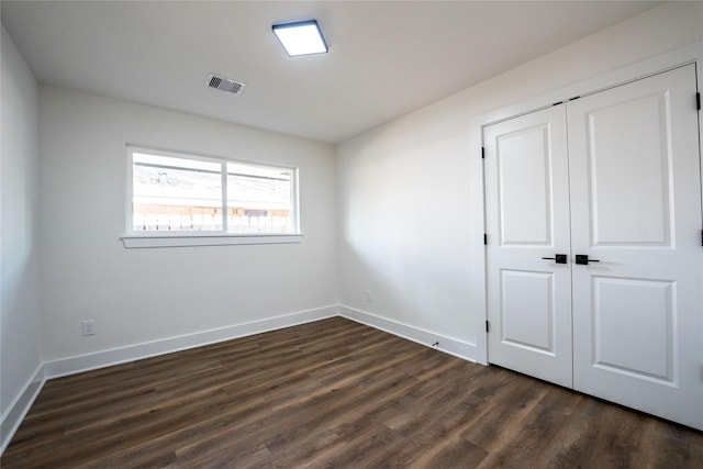 unfurnished bedroom with dark wood-type flooring and a closet