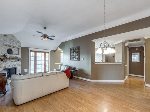 living room with a fireplace, lofted ceiling, ornamental molding, ceiling fan, and light hardwood / wood-style flooring