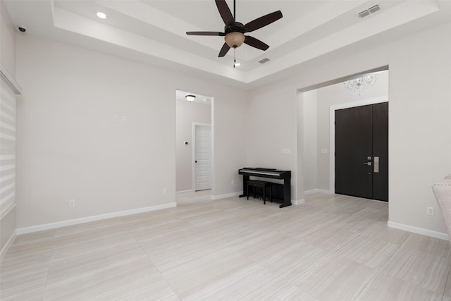 tiled spare room with a raised ceiling and ceiling fan