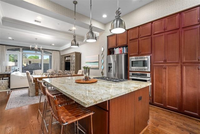 kitchen featuring light stone counters, decorative light fixtures, a center island, dark hardwood / wood-style flooring, and stainless steel appliances