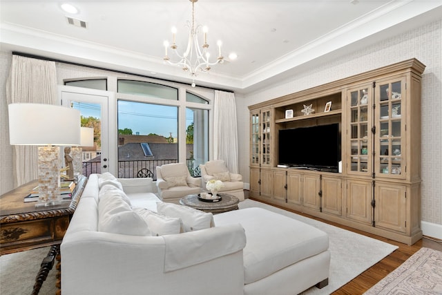 living room featuring crown molding, a notable chandelier, and light hardwood / wood-style floors