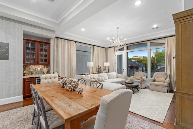 dining room featuring dark hardwood / wood-style floors, beverage cooler, a notable chandelier, crown molding, and bar area