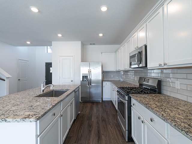 kitchen featuring dark wood-type flooring, sink, white cabinetry, appliances with stainless steel finishes, and a kitchen island with sink