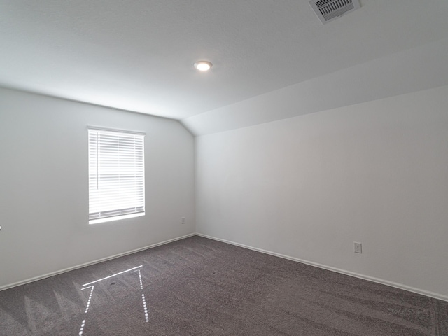 bonus room with lofted ceiling and dark carpet