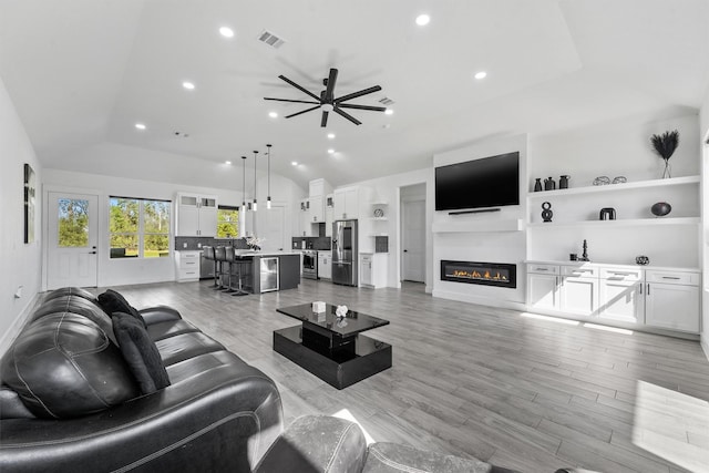 living room with lofted ceiling, ceiling fan, and light hardwood / wood-style flooring