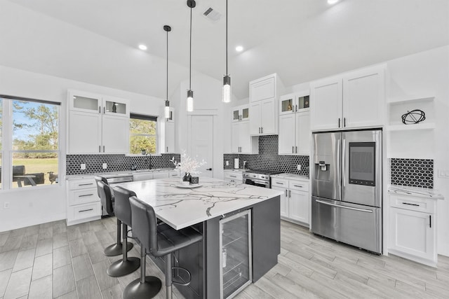 kitchen featuring white cabinetry, appliances with stainless steel finishes, a center island, and light stone counters