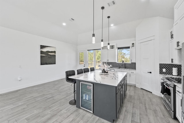 kitchen with decorative light fixtures, white cabinets, a kitchen breakfast bar, high end stainless steel range oven, and a center island