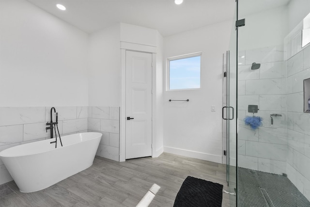 bathroom with tile walls, hardwood / wood-style floors, and separate shower and tub