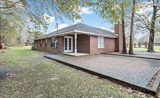 back of property with a patio, a lawn, central air condition unit, and french doors