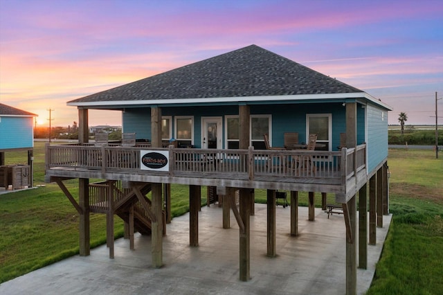 back house at dusk featuring a carport, a yard, and central AC unit