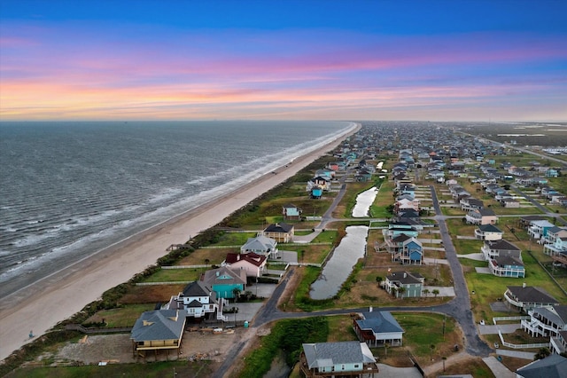 aerial view at dusk with a beach view and a water view