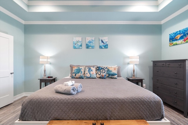 bedroom with ornamental molding, light hardwood / wood-style floors, and a raised ceiling