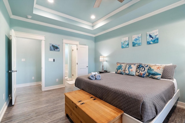 bedroom with connected bathroom, hardwood / wood-style floors, a tray ceiling, and ceiling fan