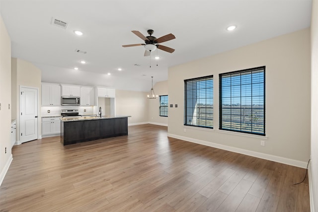 unfurnished living room with sink, ceiling fan with notable chandelier, and light hardwood / wood-style flooring