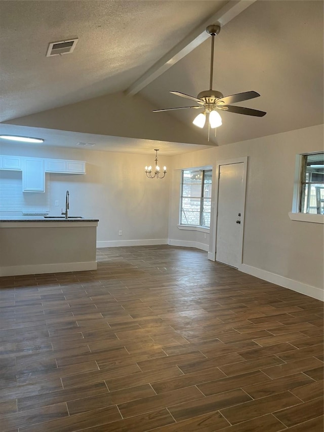 unfurnished living room featuring sink, vaulted ceiling with beams, ceiling fan with notable chandelier, and a textured ceiling