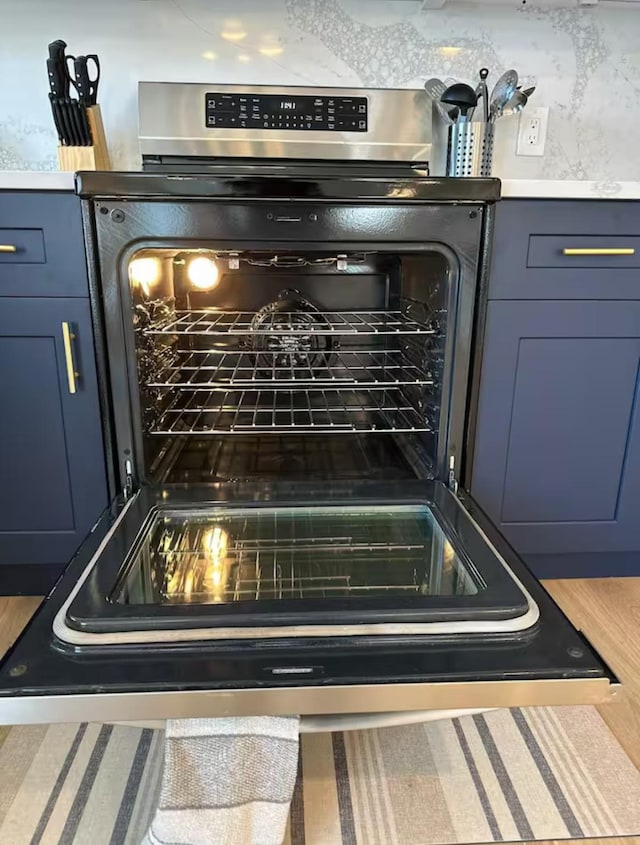 room details featuring blue cabinetry and stainless steel range with electric cooktop