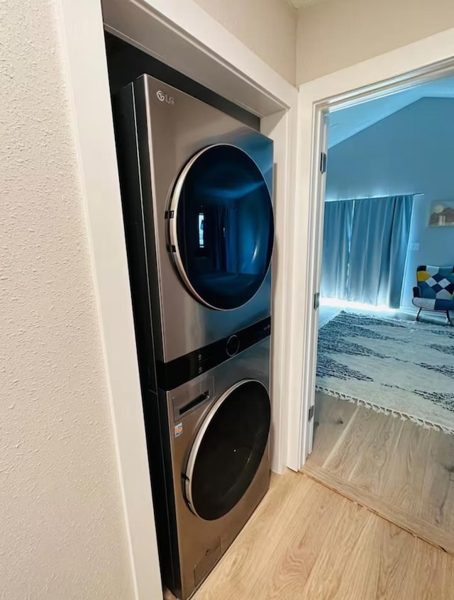 washroom featuring hardwood / wood-style flooring and stacked washer / drying machine