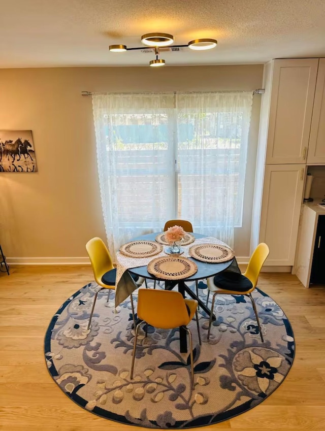 dining space with a textured ceiling and light hardwood / wood-style flooring