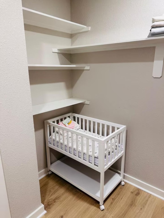 bedroom with wood-type flooring and a crib