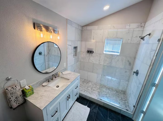 bathroom with tile patterned flooring, vanity, lofted ceiling, and a tile shower