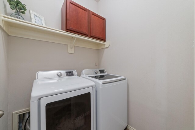 clothes washing area featuring cabinets and washer and clothes dryer