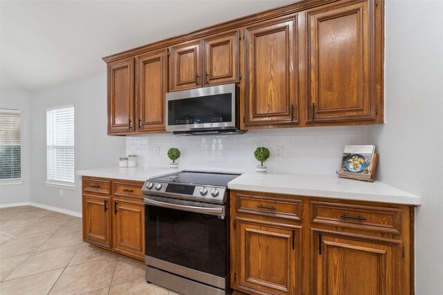 kitchen with stainless steel appliances, tasteful backsplash, vaulted ceiling, and light tile patterned floors