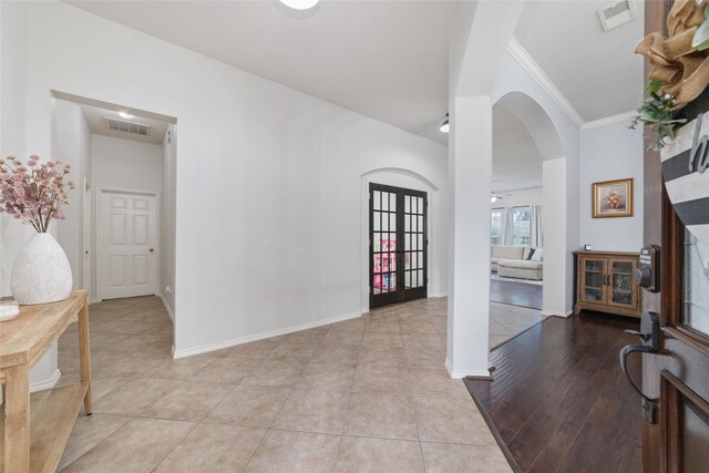 tiled entryway with ornamental molding and french doors