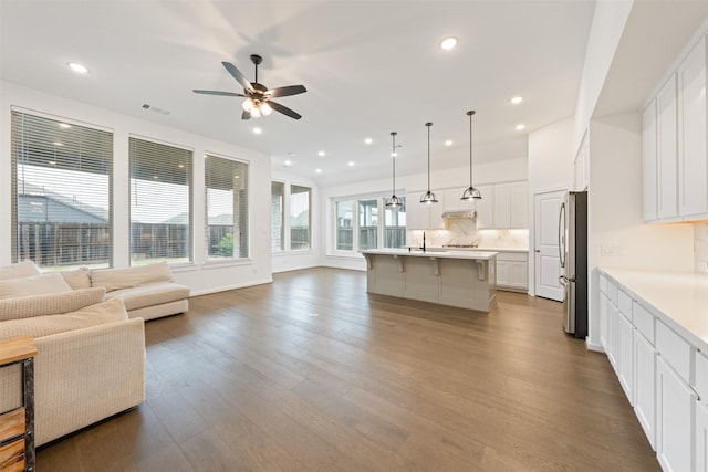 kitchen with tasteful backsplash, a kitchen breakfast bar, open floor plan, wood finished floors, and freestanding refrigerator