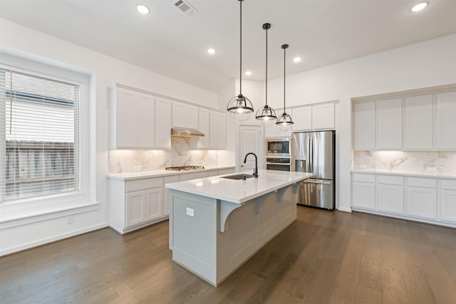 kitchen featuring visible vents, appliances with stainless steel finishes, dark wood-type flooring, under cabinet range hood, and a sink