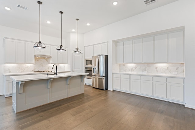 kitchen featuring appliances with stainless steel finishes, visible vents, under cabinet range hood, and wood finished floors